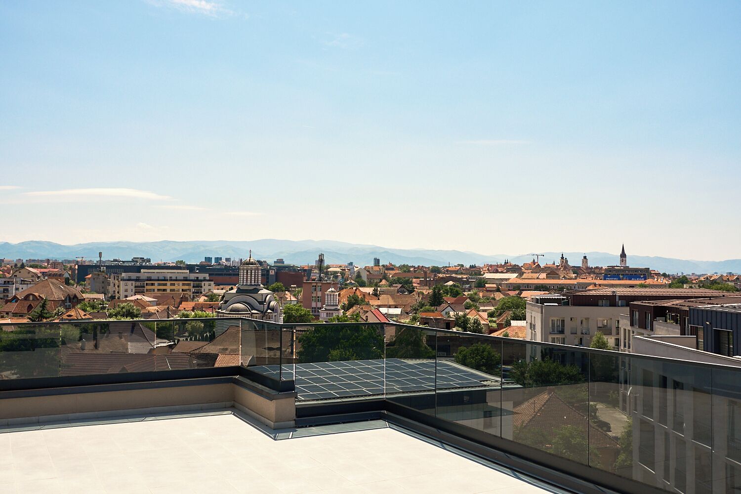 Une terrasse sur le toit offrant une vue dégagée sur le paysage urbain et les montagnes lointaines.
