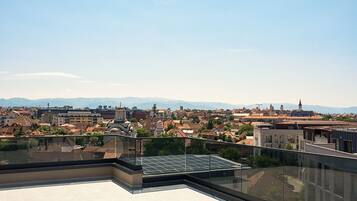 Une terrasse sur le toit offrant une vue dégagée sur le paysage urbain et les montagnes lointaines.