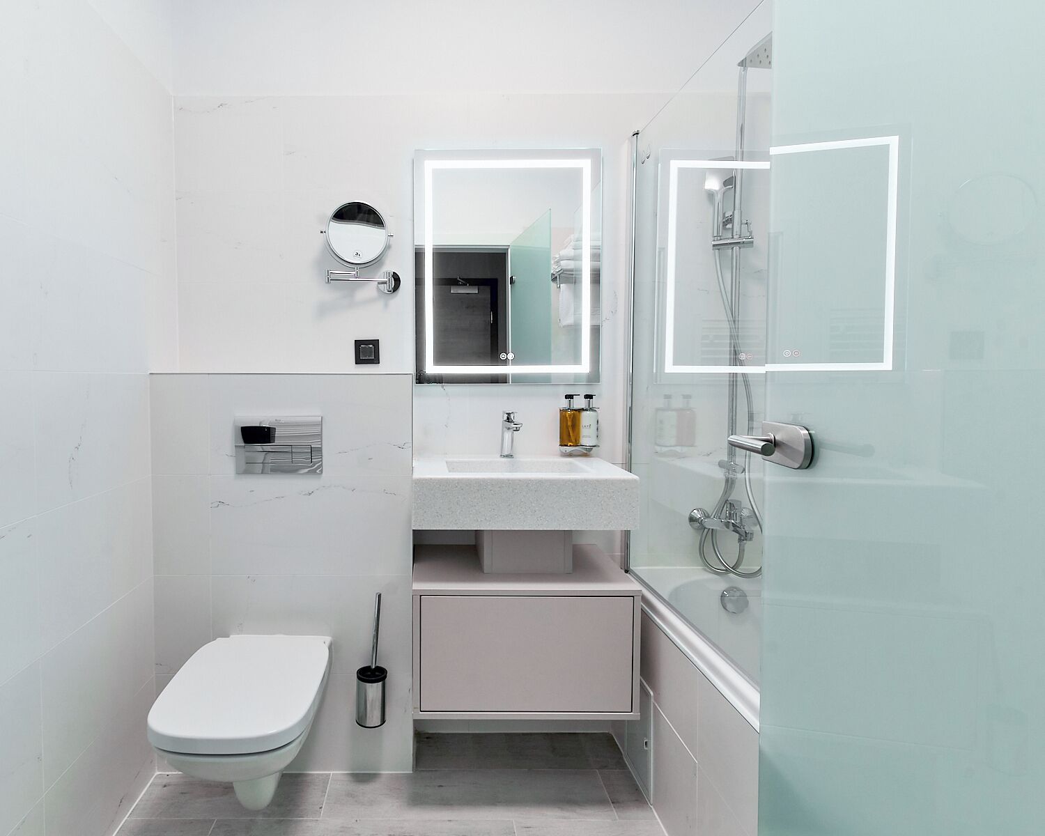 Een kleine badkamer met toilet, wastafel met spiegel en douche.