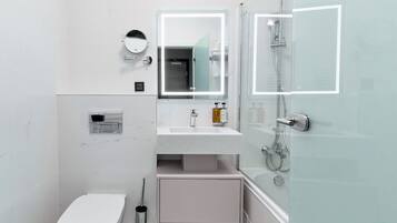 Een kleine badkamer met toilet, wastafel met spiegel en douche.