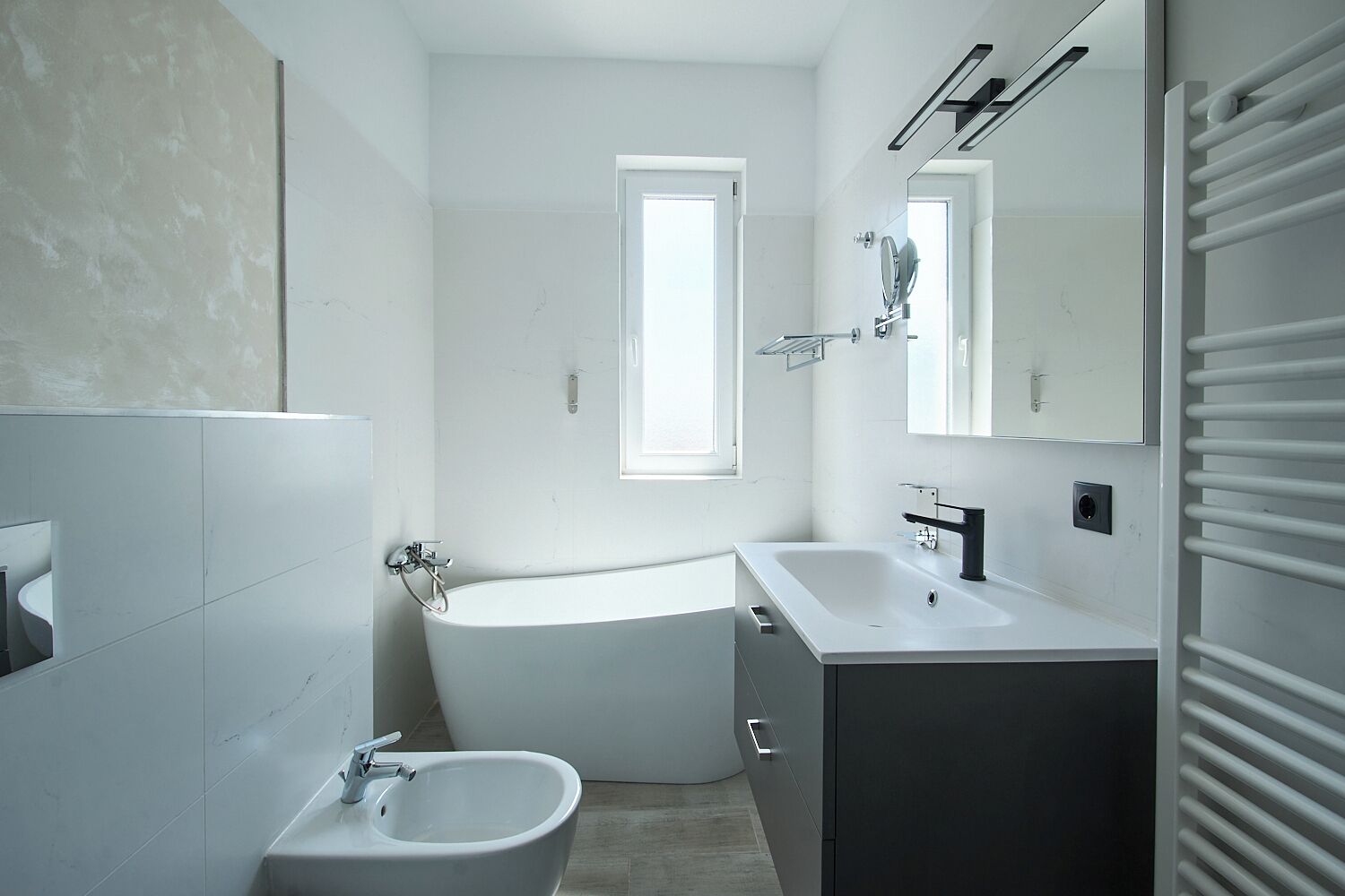 Un baño moderno con bañera, lavamanos, bidé y un espejo grande.