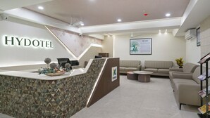 A reception area with a modern design, including a reception desk, seating area, and a framed informational poster on the wall. - Treebo Premium Hydotel, Hi-Tech City (Hyderabad)