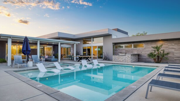 Un espace piscine extérieur moderne, doté de chaises longues et d’une table à manger.