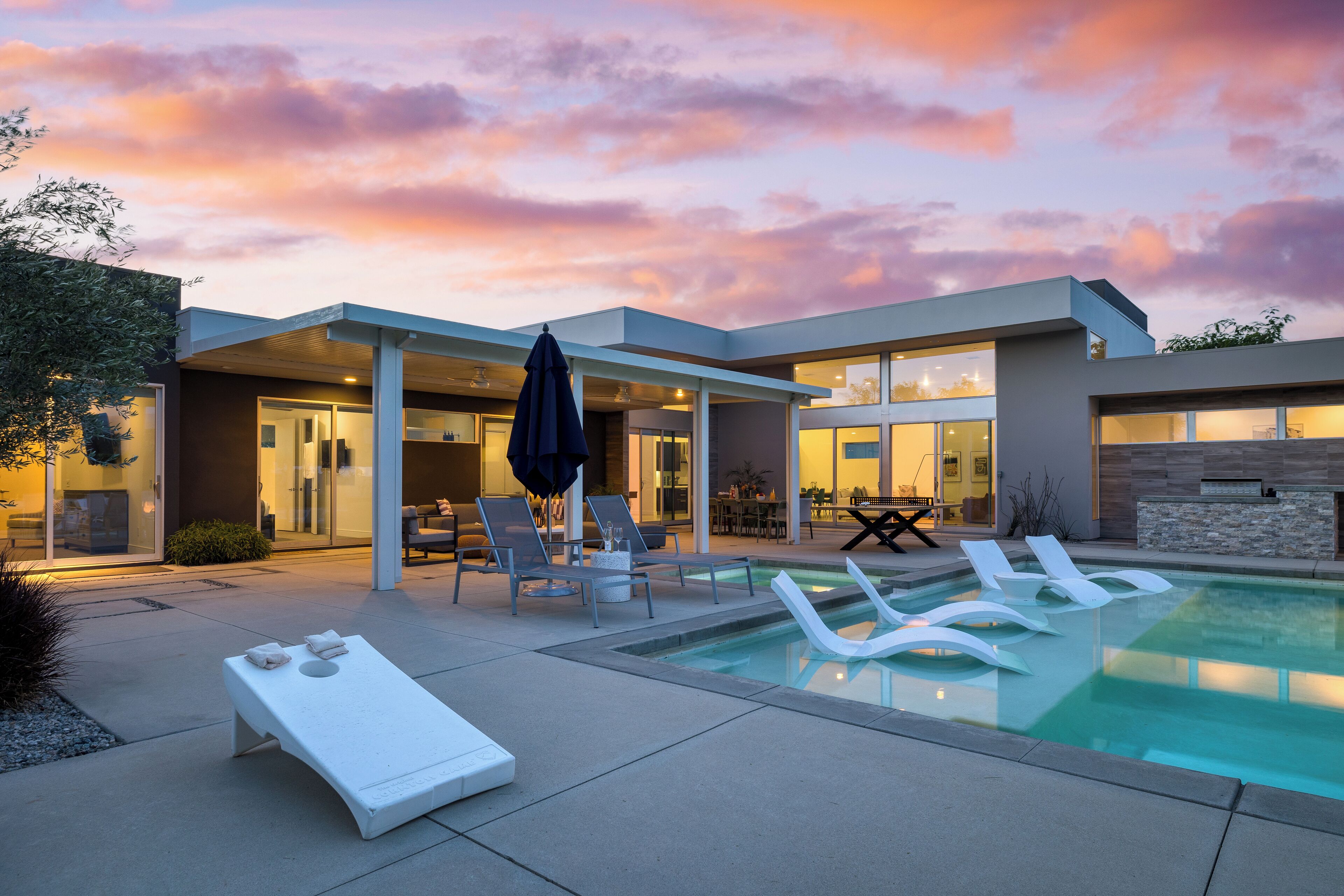 Une maison moderne dotée d’une piscine, de chaises longues et d’un espace patio.