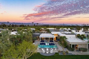 A modern resort with a swimming pool, outdoor seating, and a view of the mountains. - 2 Villas | Pool+Spa, Putting Green, Bocce | Polo Villas Solstice by AvantStay (La Quinta)