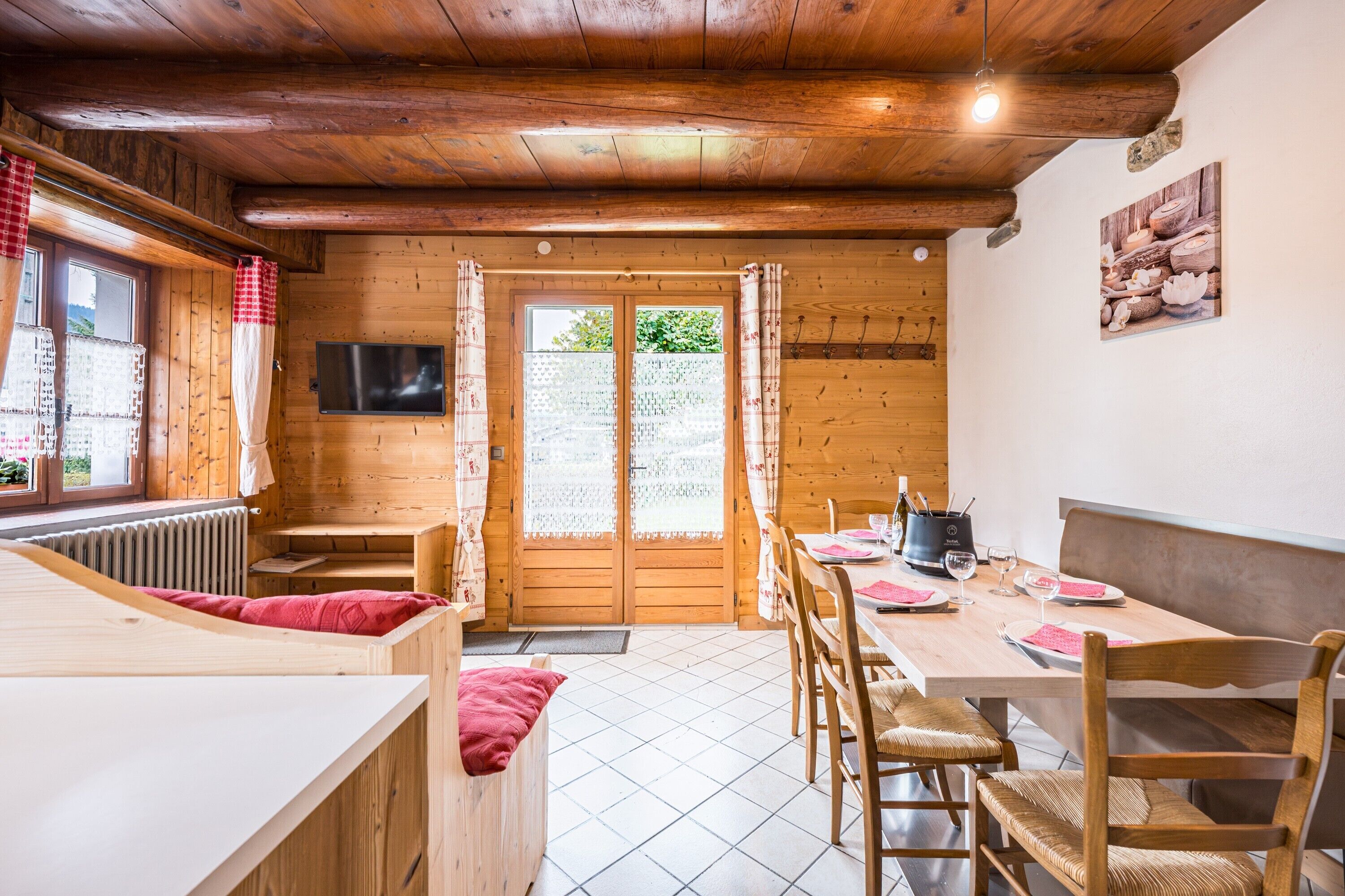 Un interior de madera con zona de comedor, un banco y un televisor.