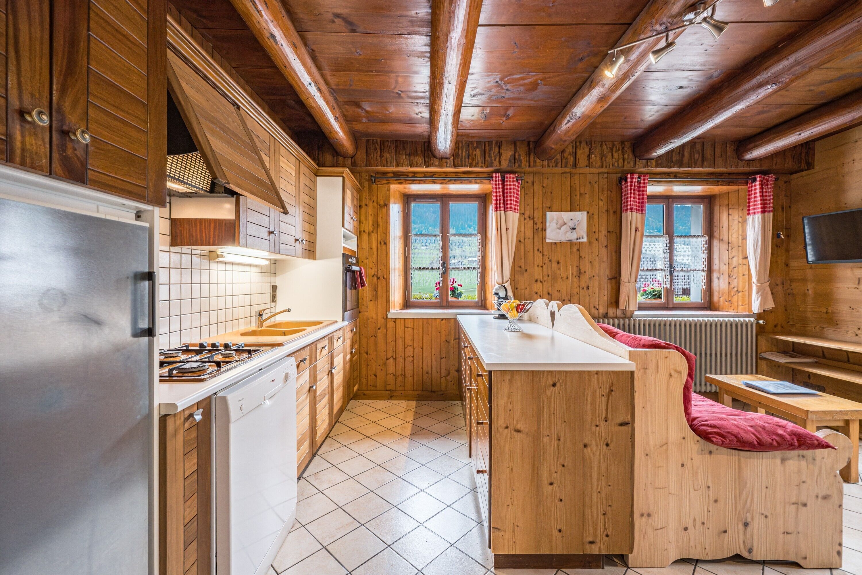 A wooden cabin interior with a kitchen, dining area, and a cozy seating space.