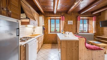 A wooden cabin interior with a kitchen, dining area, and a cozy seating space.