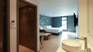 A modern hotel room with a large bed, a bedside table, a built-in TV, and a large bathroom sink. - KOO Hotel (Pak Kret)