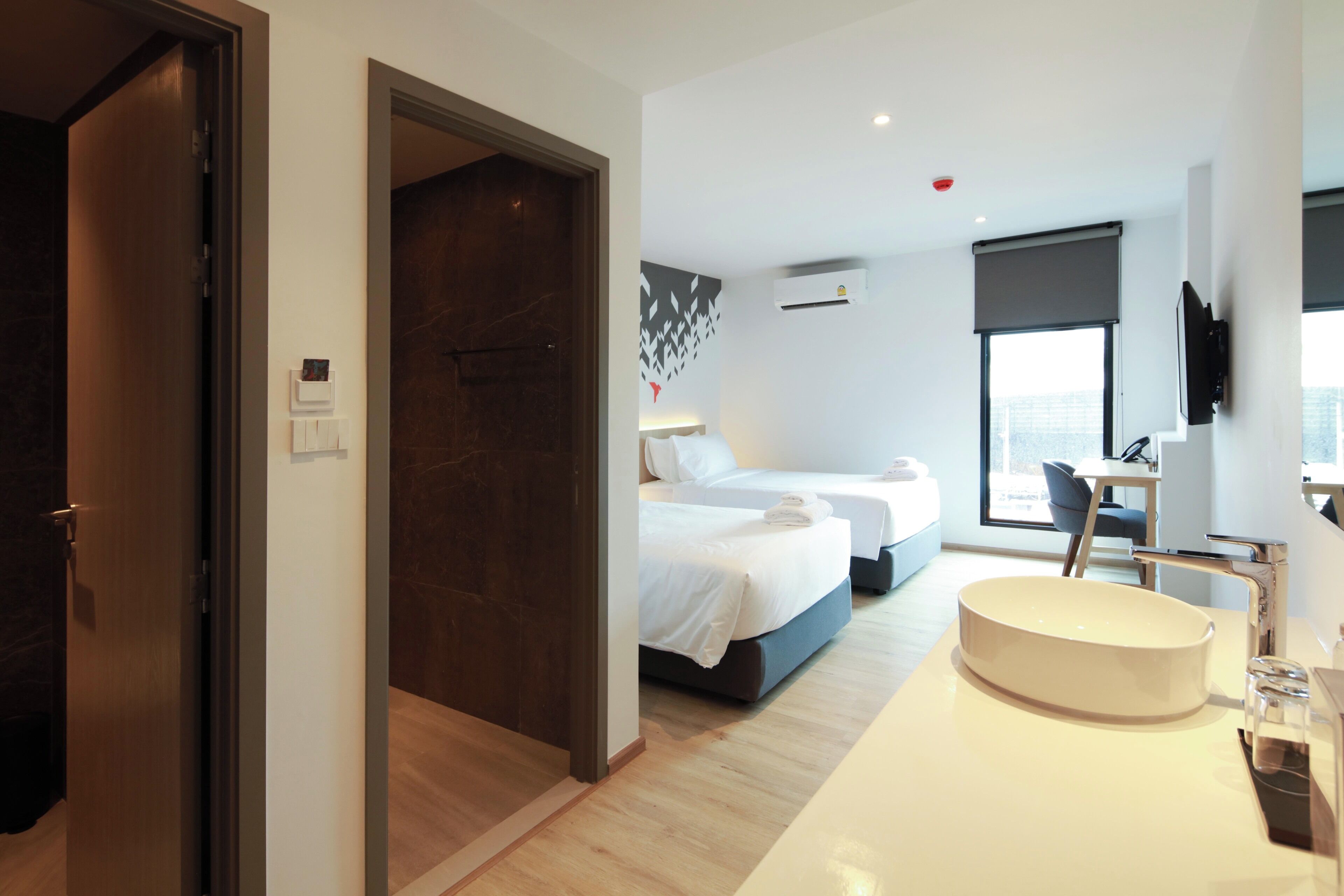 Una moderna camera d'hotel con un letto grande, una scrivania, un lavandino rotondo e vista sulla città.