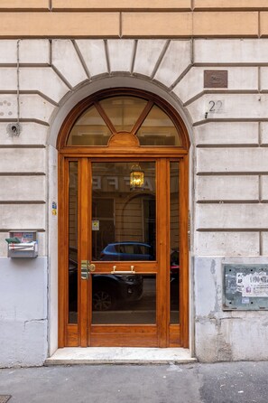 A wooden door with a glass panel, a mailbox, and a utility box on the wall.