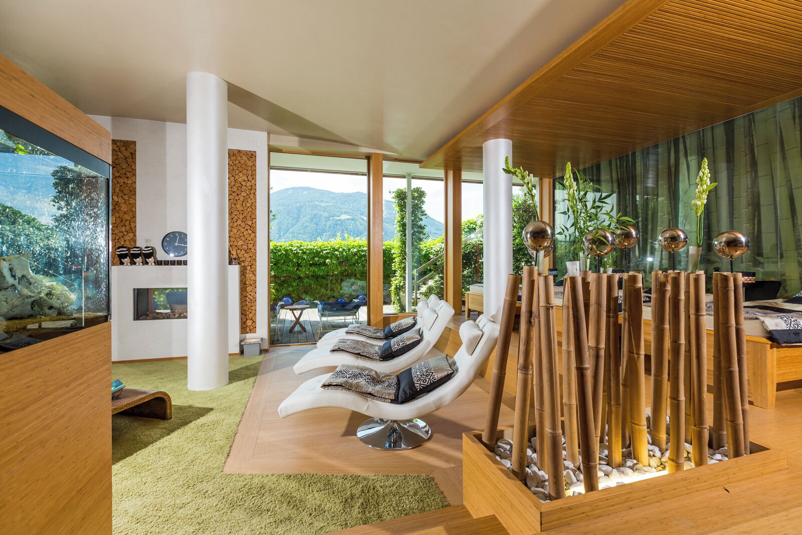 A modern living room with a large aquarium, comfortable seating, and a view of the outdoors.
