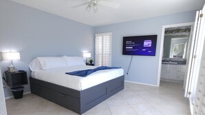 A bedroom with a bed, a ceiling fan, a TV, and a bathroom visible through an open door. - Scottsdale Adobe Retreat with Private Pool & Hot Tub, King beds, Fast 5G Wifi. (Scottsdale)