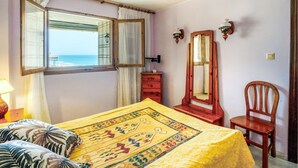 Un dormitorio con cama, cómoda, silla y un espejo grande.