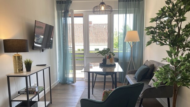 Un salon moderne avec un canapé, une table basse, un téléviseur et une plante en pot.