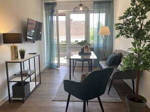 A modern living room with a sofa, a coffee table, a TV, and a potted plant. - Stranddistel 4 - "Stranddistel" vacation home with 5 residential units... (Dahme)