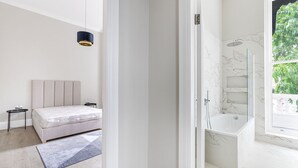 Un dormitorio moderno con cama, mesitas de noche y una mesita auxiliar.