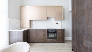 Una cocina moderna con armarios de madera, horno empotrado y encimera blanca.