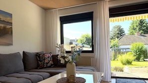 A modern living room with a sofa, a coffee table, and a window with curtains.