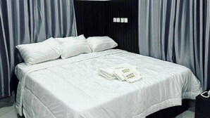 A neatly made bed with white linens and pillows, a black headboard, and grey curtains. - Bott Apartment (Abuja)