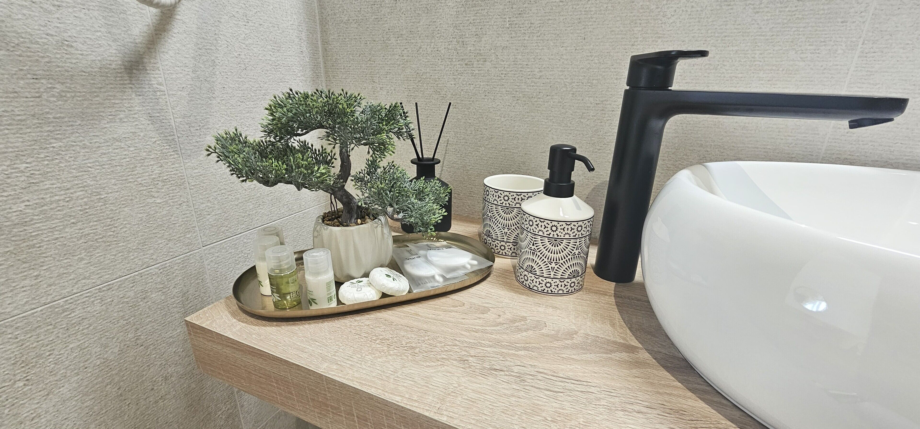 Un meuble-lavabo de salle de bain avec un lavabo blanc, un robinet noir et un plateau contenant des articles de toilette.