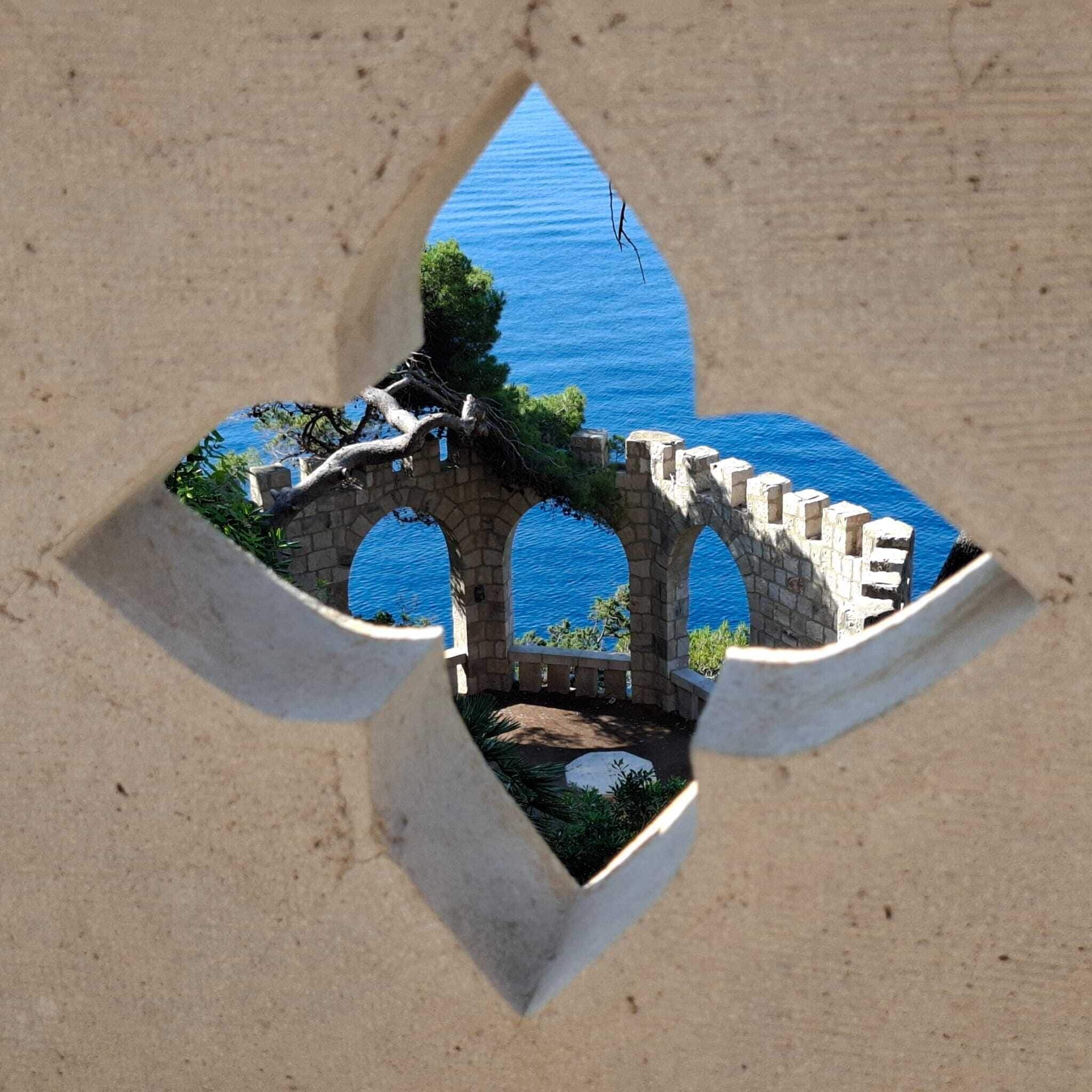 Un pont en pierre, doté d’arches, enjambe un cours d’eau et est entouré de verdure.