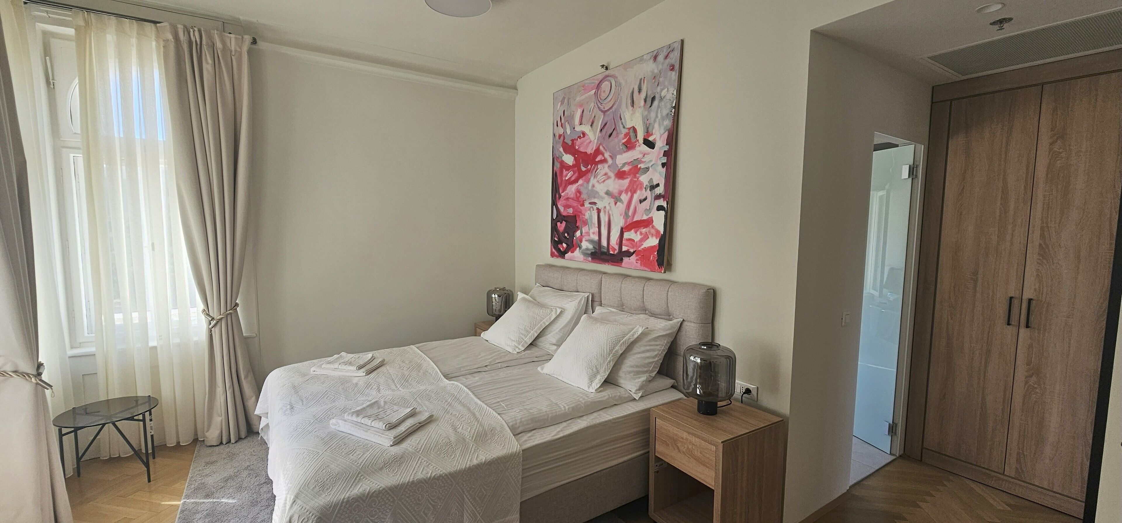 Une chambre à coucher avec un lit, une table de chevet, un tableau et une armoire.