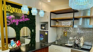 Una cocina moderna con un letrero de neón, taburetes de bar, una araña y un microondas.