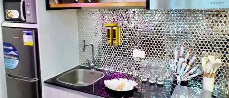 A compact kitchen with a microwave, refrigerator, and a sink.