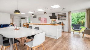 Una cocina moderna con una isla central, armarios blancos y un área de comedor con una mesa redonda y sillas.