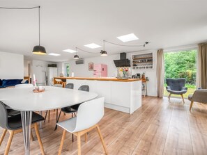 Une cuisine moderne dotée d’un îlot central, de meubles blancs et d’un coin repas avec une table ronde et des chaises.
