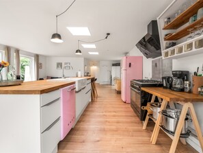Une cuisine moderne avec un plan de travail en bois, un réfrigérateur rose et une cuisinière.