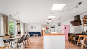 Una cocina moderna con una isla central, suelo de madera y un comedor con sillas y una mesa.