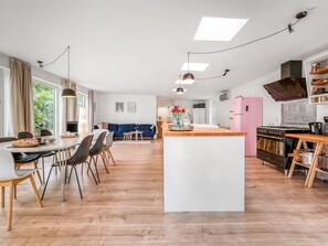 Une cuisine moderne dotée d’un îlot central, de revêtements de sol en bois et d’un coin repas avec des chaises et une table.