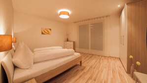 Une chambre à coucher avec un lit, une table de chevet, une armoire et une fenêtre avec des rideaux.