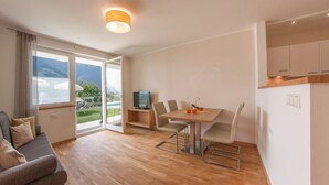Un salon moderne avec un canapé, une table à manger et des chaises, ainsi qu’un téléviseur.