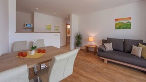 Un salon moderne avec une table à manger en bois, un canapé et une lampe.