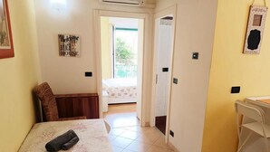 A room with a bed, a desk, and a door leading to a balcony. - Raffaello Beach Apartment Savona, 50 m from the sea, WIFI, AC, equipped kitchen (Savona)