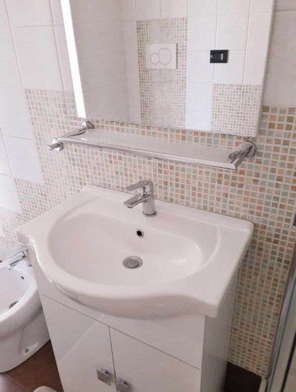A bathroom with a white sink, a mirror, and a toilet.