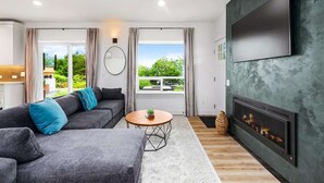 A modern living room with a grey sofa, a round coffee table, and a fireplace.