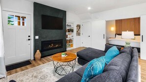 A modern living room with a fireplace, a sofa, a coffee table, and a TV mounted on the wall.