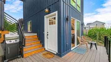 A modern house with a deck, a barbecue grill, and outdoor furniture.