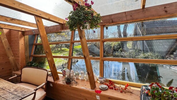 Ein gemütliches Zimmer mit Holzvertäfelung, einem großen Fenster und Blick auf eine natürliche Landschaft.