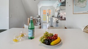 A dining area with a table set for two, a bottle of water, and a bowl of fruit.