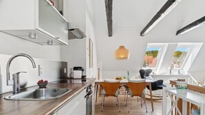 A modern kitchen with a Bosch dishwasher, a stainless steel sink, and a dining area with wooden chairs and a white table.