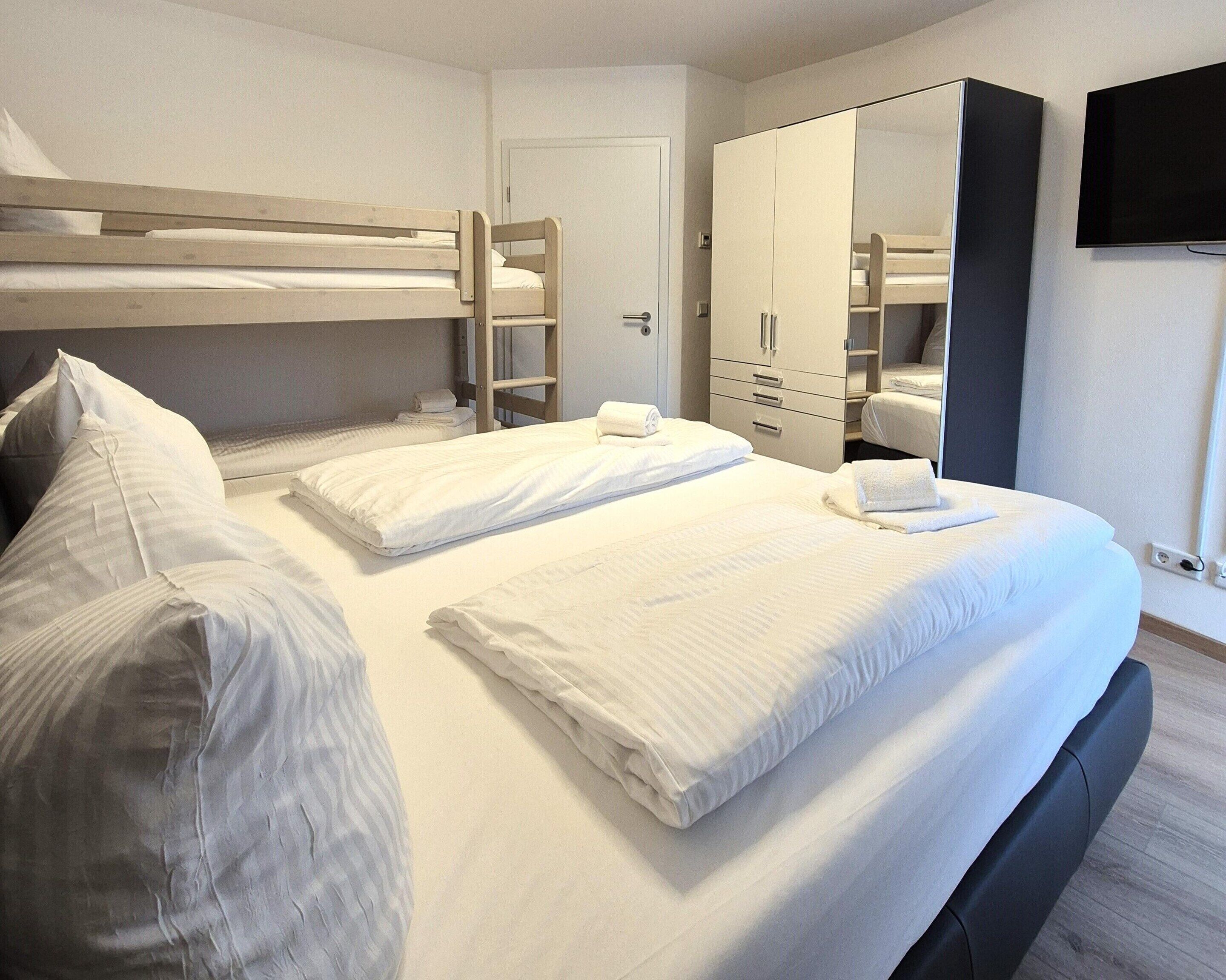 A hotel room with a bunk bed, a wardrobe, a mirror, and a television.