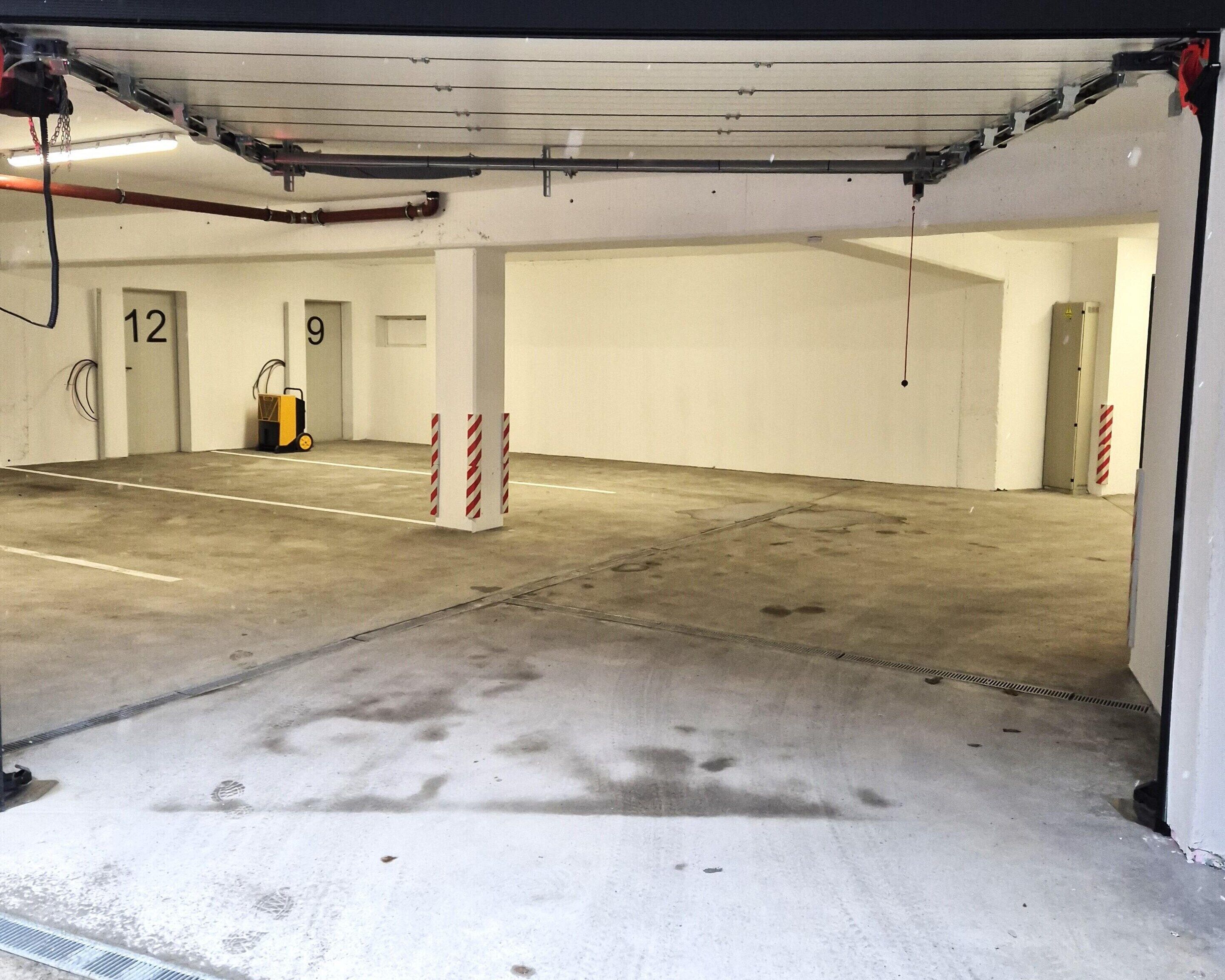 A parking garage with concrete floors, numbered parking spaces, and red and white striped columns.