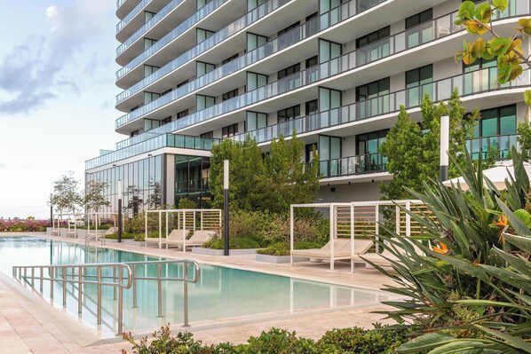 Un hôtel moderne doté d’une piscine, d’un espace extérieur aménagé et d’une végétation luxuriante.