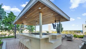 A covered outdoor bar area with seating and a pool.