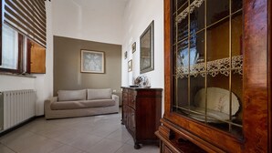 A room with a radiator, a sofa, a wooden cabinet, and a large mirror.
